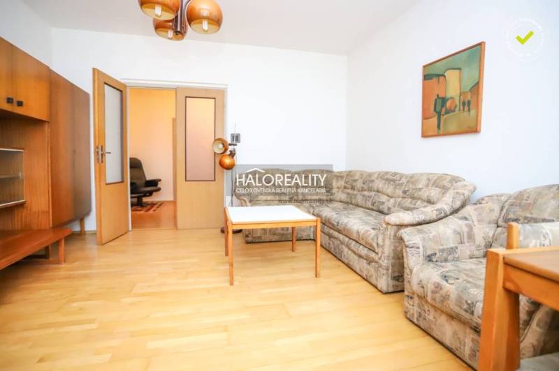 Wohnzimmer einer 3-Zimmer-Wohnung mit Sofa, Tisch und Holzboden.