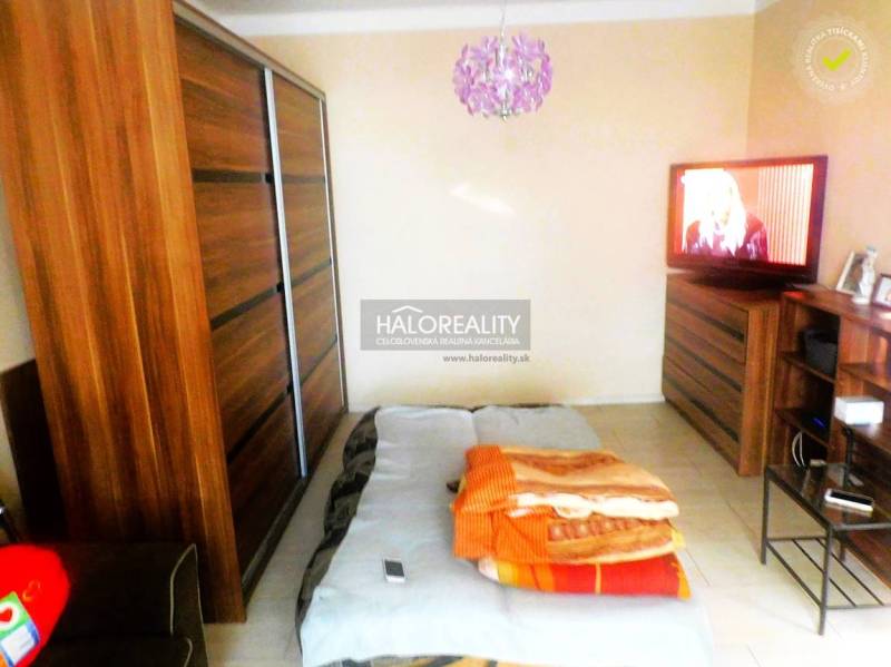 Schlafzimmer in einer 2-Zimmer-Wohnung mit Bett, Sofa und Schrank mit Holzdekor.