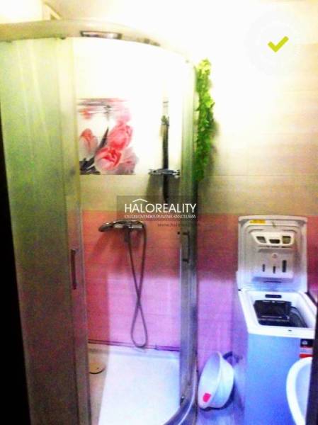 Badezimmer in einer 2-Zimmer-Wohnung mit Dusche und Waschmaschine, farblich in Rosa gehalten.