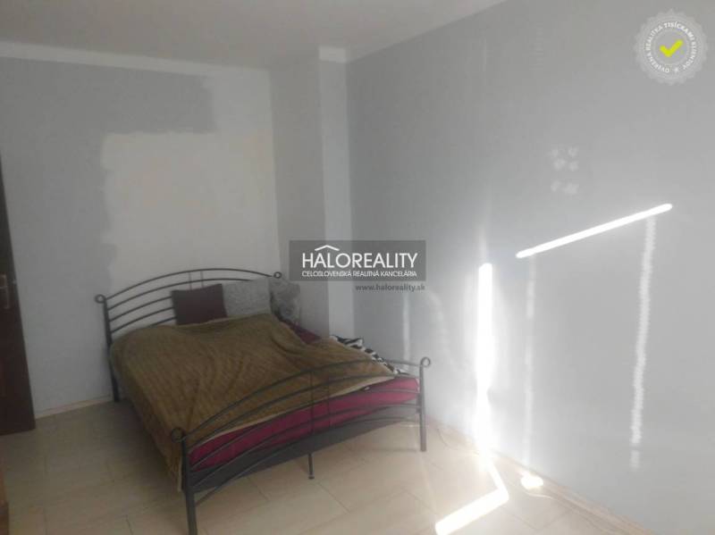 Schlafzimmer mit Metallbett und weißen Wänden in einer Zweizimmerwohnung.