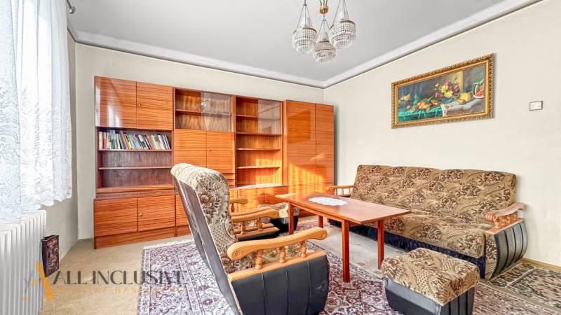 Wohnzimmer in einem Einfamilienhaus mit Sesseln, Teppich, Bücherregal und Vorhängen.