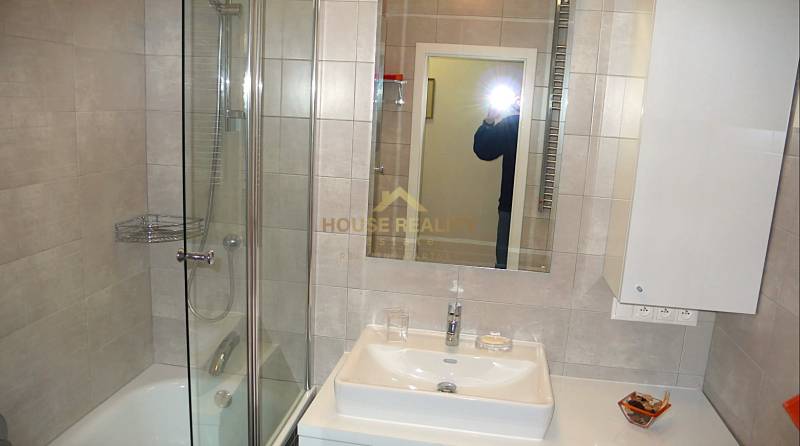 Badezimmer mit Dusche, Spiegel und Waschbecken in einer 4-Zimmer-Wohnung.