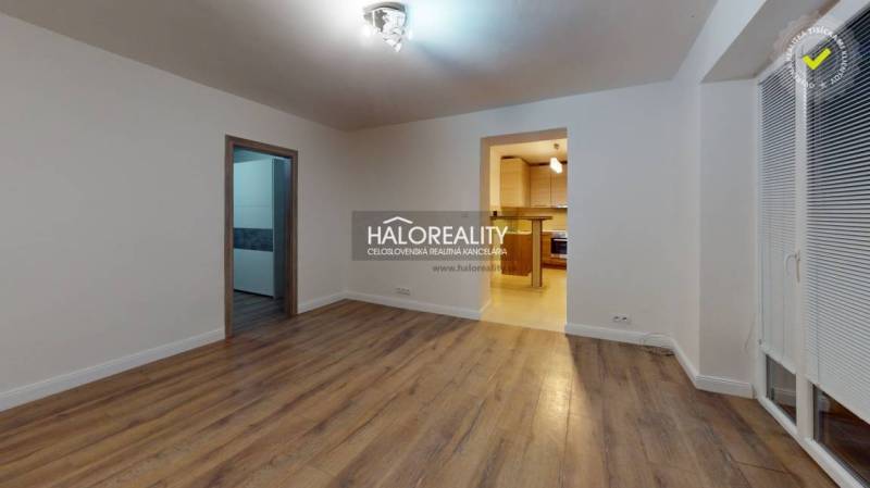 Wohnzimmer in einer Zweizimmerwohnung mit Holzboden und Zugang zur Küche.