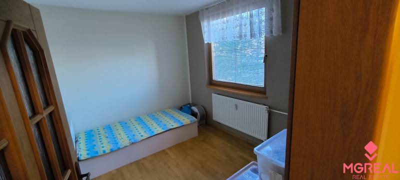 Gemütliches Zimmer in einer 3-Zimmer-Wohnung mit Bett und Holzboden.