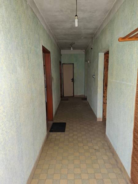 Ein Flur in einem Einfamilienhaus mit hellgrünen Wänden, Fliesenboden und einfacher Beleuchtung.