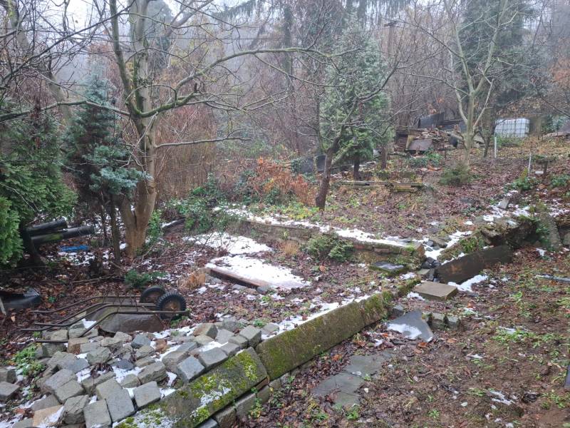 Garten beim Einfamilienhaus in der Búdková in Bratislava - Staré Mesto, mit einem kaputten Zaun und Bäumen.
