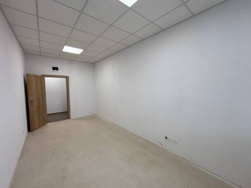 Innenraum eines Büros mit weißen Wänden, abgehängter Decke und offenen Türen.