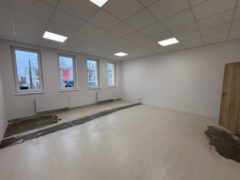 Leere Büros mit weißen Wänden, Deckenbeleuchtung und einem Boden in Holzoptik.