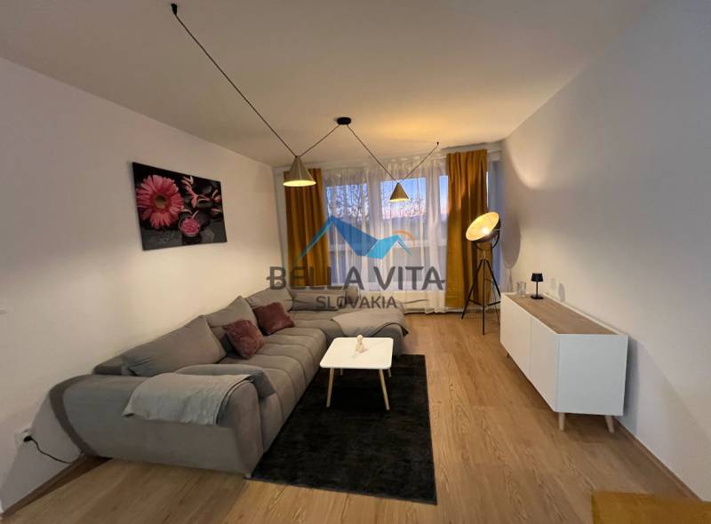 Wohnzimmer in einer Zweizimmerwohnung mit Sofa und Holzboden.