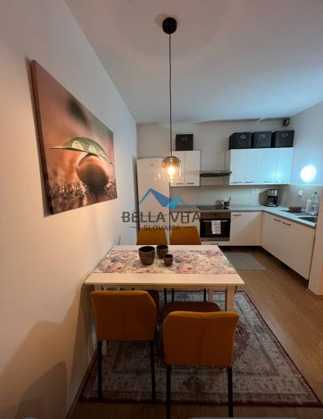 Die Küche einer 2-Zimmer-Wohnung mit einem Esstisch, gelben Stühlen und einem Holzboden.