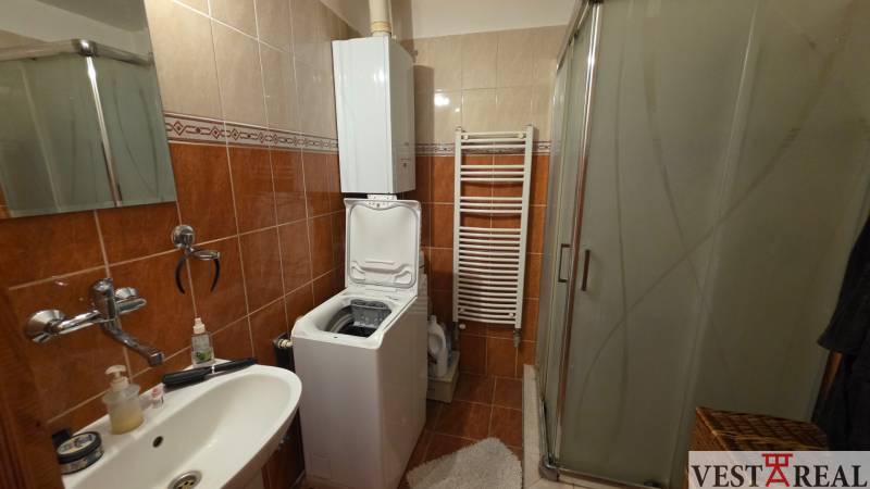 Badezimmer in einer 3-Zimmer-Wohnung mit Waschmaschine, Duschkabine und Keramikfliesen.