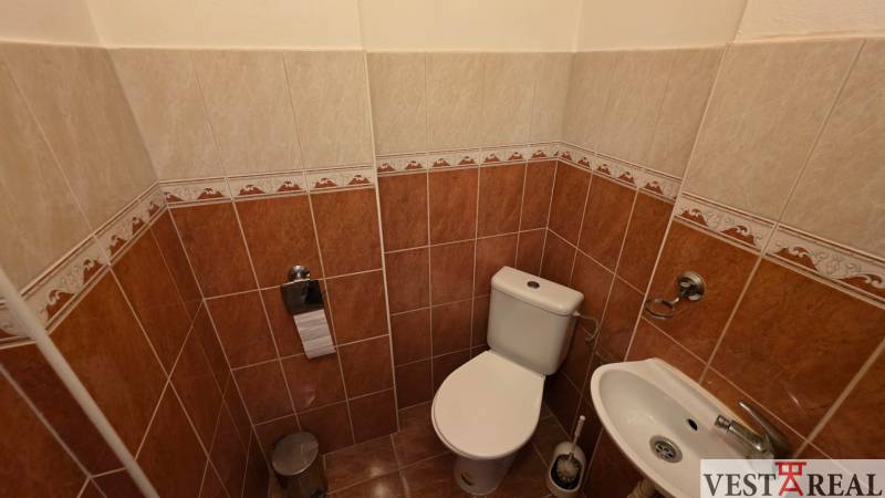 Toilette mit Bidet in einer 3-Zimmer-Wohnung, gefliest mit braunen und cremefarbenen Fliesen.