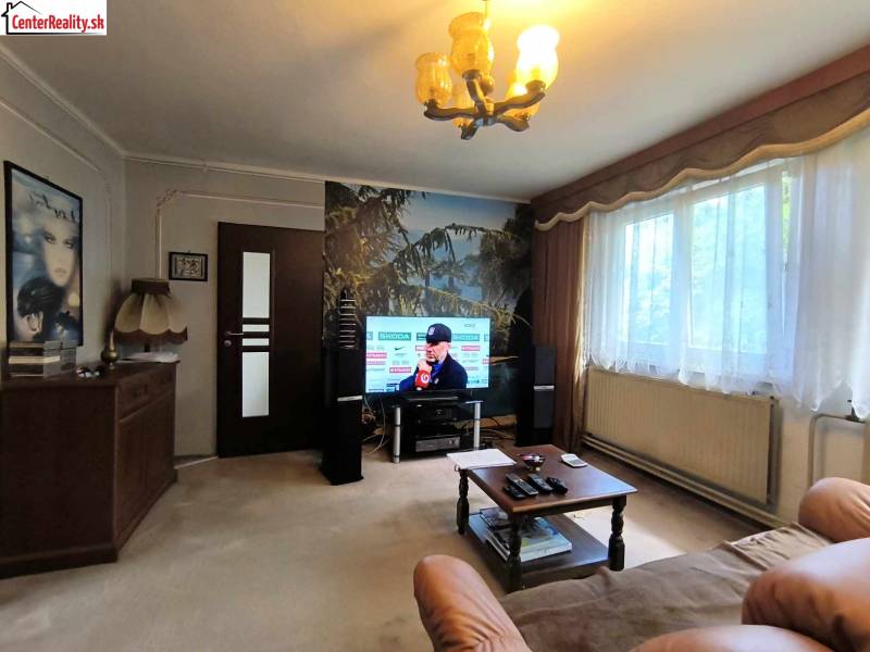 Wohnzimmer mit Fernseher, Sofa, Tisch und großem Fenster, Einfamilienhaus.