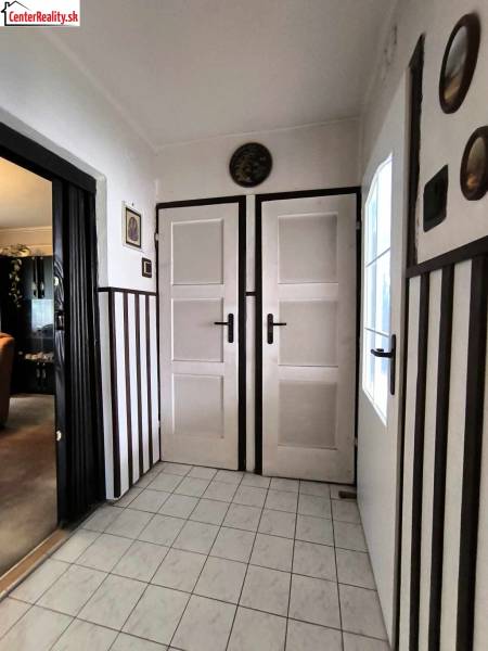 Innenraum eines Einfamilienhauses mit weißen Türen, Fliesenboden und dunkler Wandverkleidung.