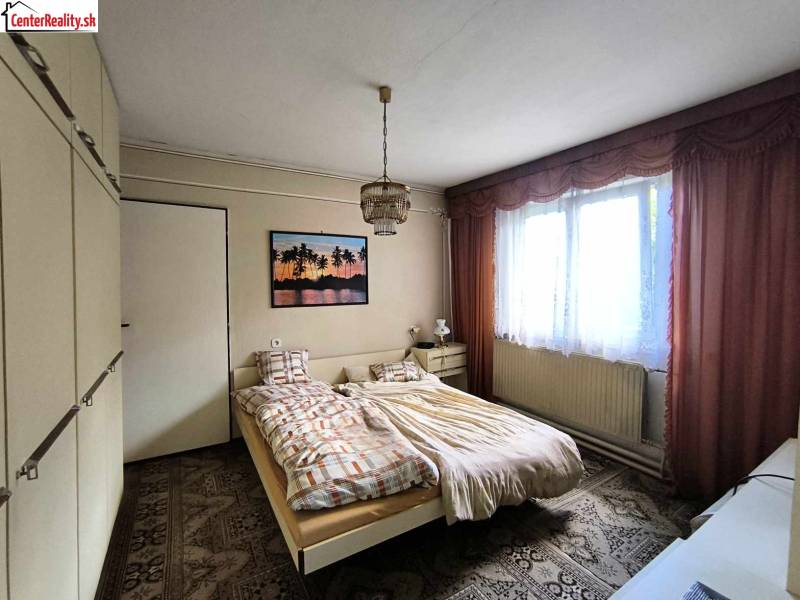 Schlafzimmer im Einfamilienhaus mit Bett, Schrank und Bild an der Wand.