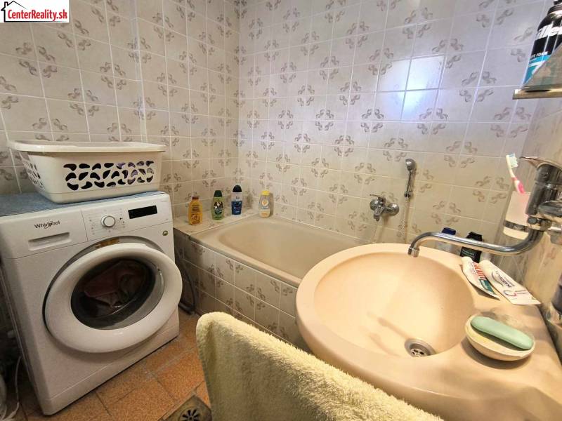 Badezimmer in einem Einfamilienhaus mit Badewanne, Waschmaschine und Waschbecken.