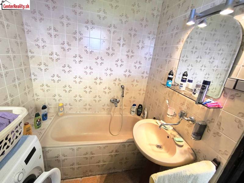 Badezimmer mit Badewanne und Waschmaschine in einem Einfamilienhaus mit Fliesen.