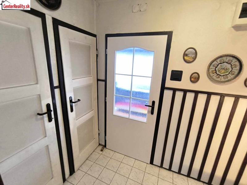 Das Innere eines Einfamilienhauses mit weißen Türen, Wanddekorationen und Fliesen.