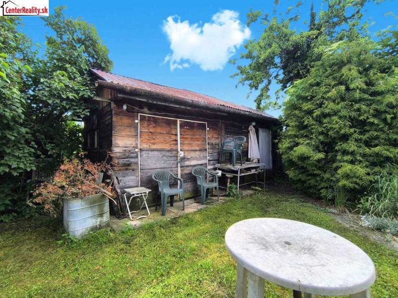 Eine Holzhütte mit Plastikstühlen im Garten eines Einfamilienhauses in Nováky.