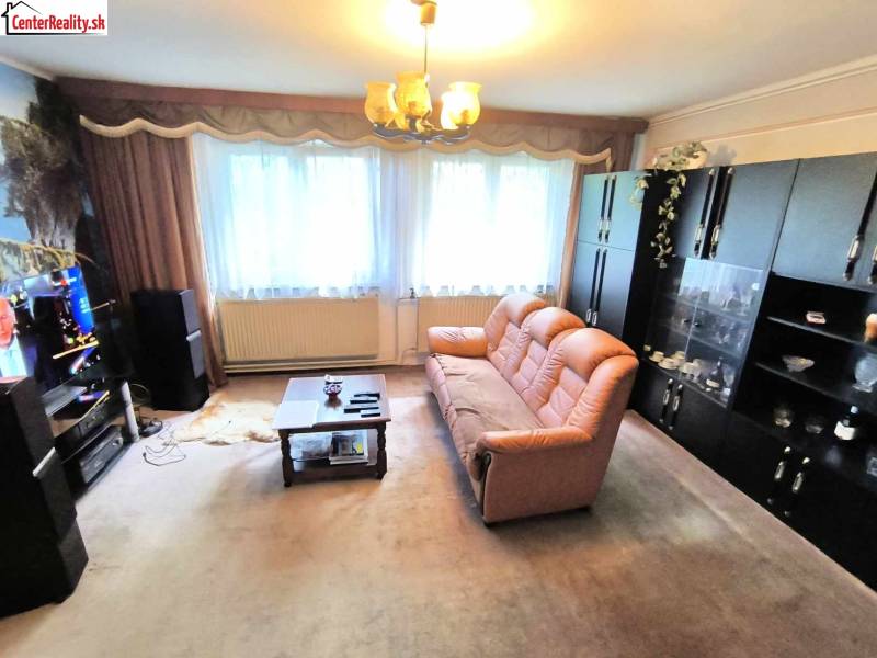 Wohnzimmer in einem Einfamilienhaus mit braunem Sofa, Schränken und einem Fernseher an der Wand.