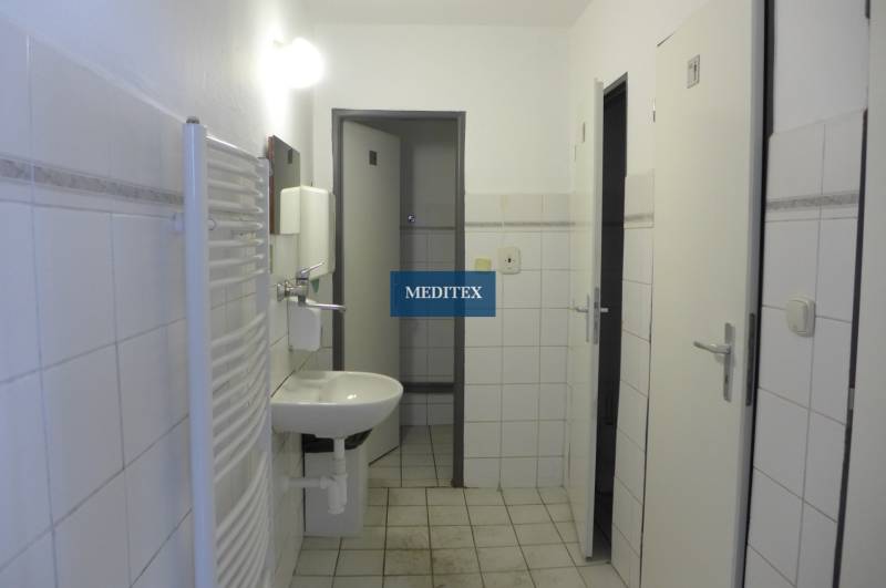 Ein weißes Badezimmer mit Waschbecken, Heizkörper und behindertengerechtem WC in Lager und Hallen.