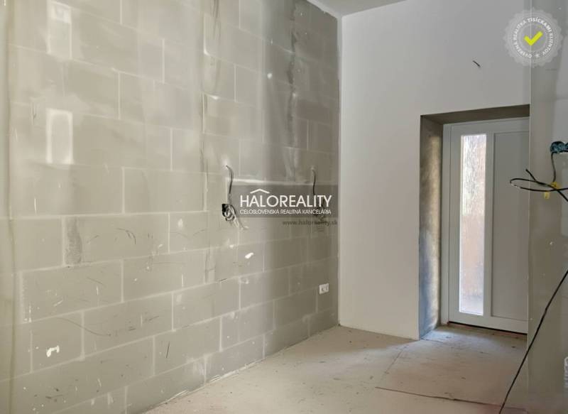 Heller Raum mit unfertigen Wänden in einem Einfamilienhaus mit Eingangstür.