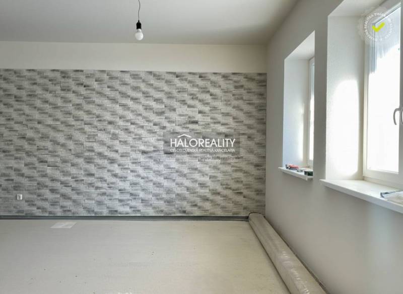 Innenraum eines Einfamilienhauses mit texturierter Wand und nicht installiertem Boden mit Holzdekor.