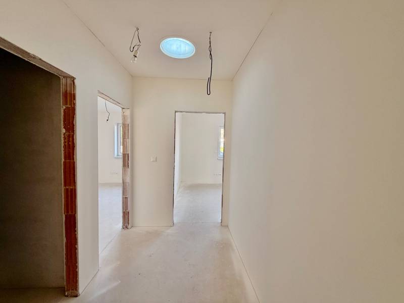 Ein Flur in einem Einfamilienhaus mit provisorischer Beleuchtung und Betonboden.