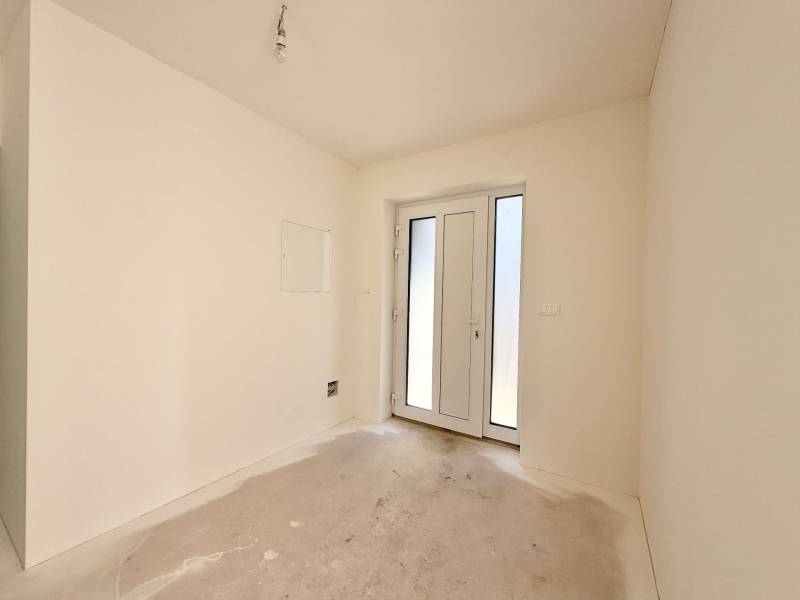 Ein leerer Raum mit französischen Türen in einem Einfamilienhaus, weiße Wände, Betonboden.