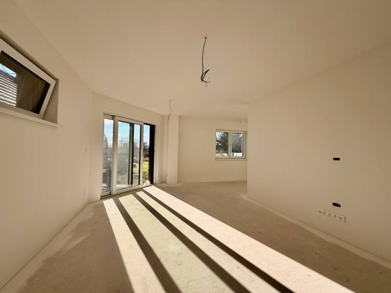 Ein geräumiges Zimmer in einem Einfamilienhaus mit großen Fenstern und Blick auf den Garten.