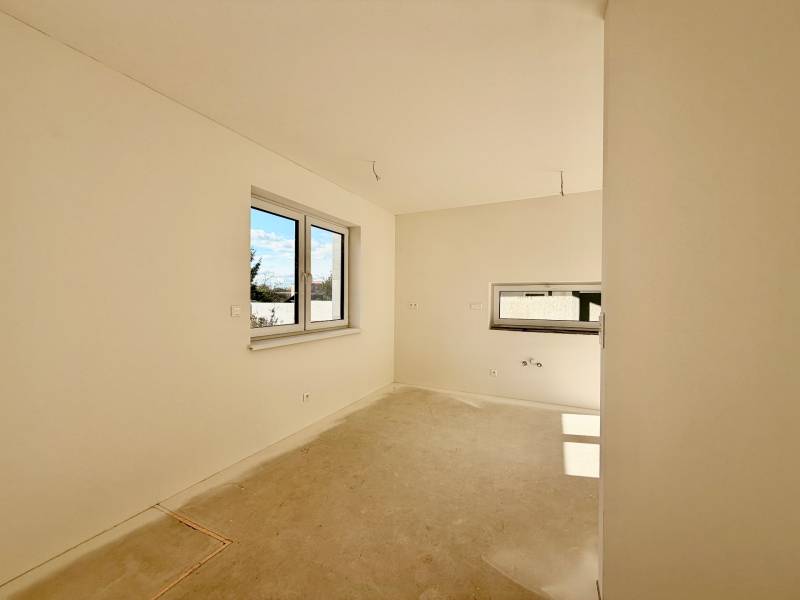 Ein leerer Raum mit Doppelfenster und Betonboden in einem Einfamilienhaus.