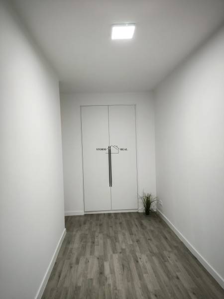 Ein weißer Raum mit Holzboden und Doppeltüren in einer Vierzimmerwohnung.