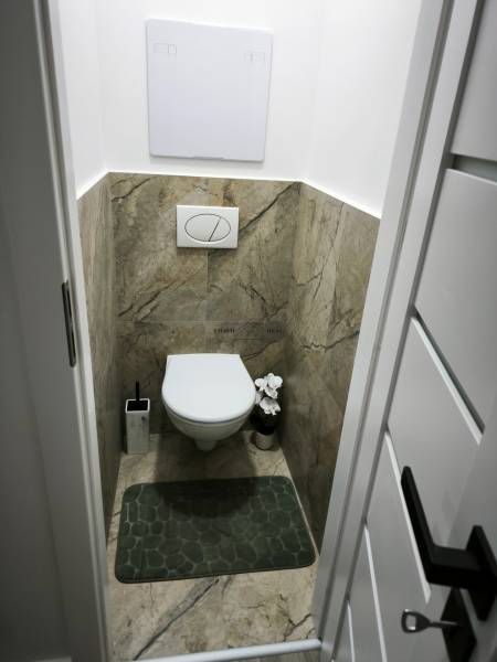 Toilette in einer 4-Zimmer-Wohnung mit Keramikfliesen und dekorativem Teppich.