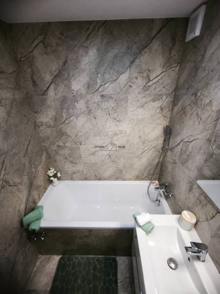 Badezimmer mit grauen Marmorkacheln und Badewanne in einer 4-Zimmer-Wohnung.