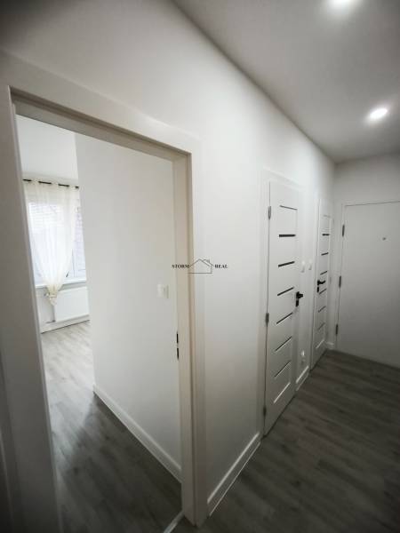 Der Flur in der 4-Zimmer-Wohnung mit weißen Türen und einem Boden in Holzoptik.