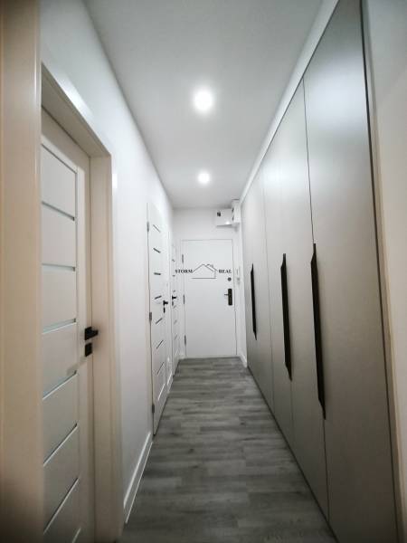 Flur mit vielen Einbauschränken und einem Boden mit Holzdekor in einer 4-Zimmer-Wohnung.