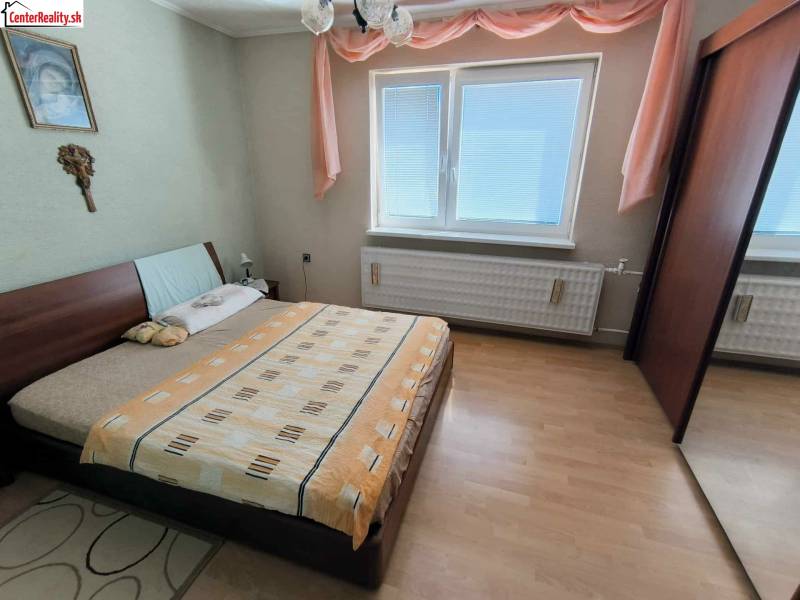 Ein Schlafzimmer in einem Einfamilienhaus mit einem Bett, einem Schrank und einem Boden mit Holzdekor.