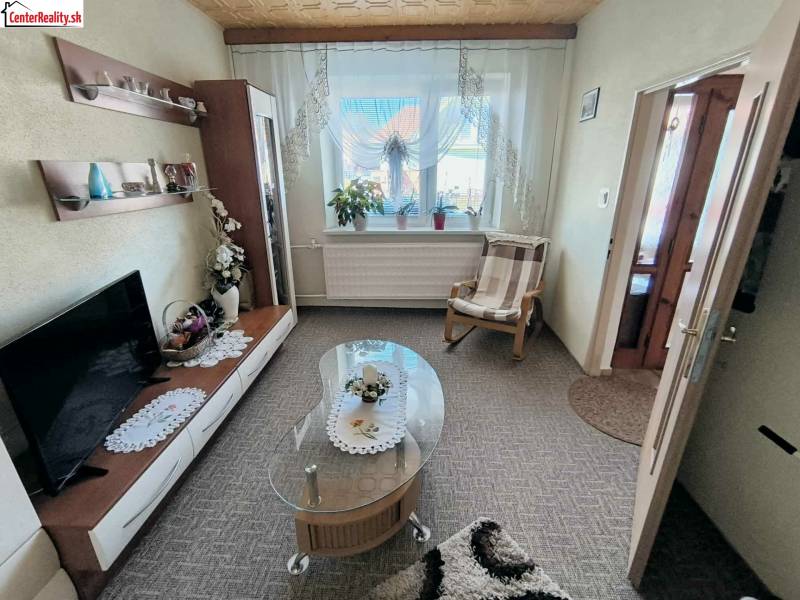 Wohnzimmer in einem Einfamilienhaus mit Teppich, Fernseher und Glastisch.