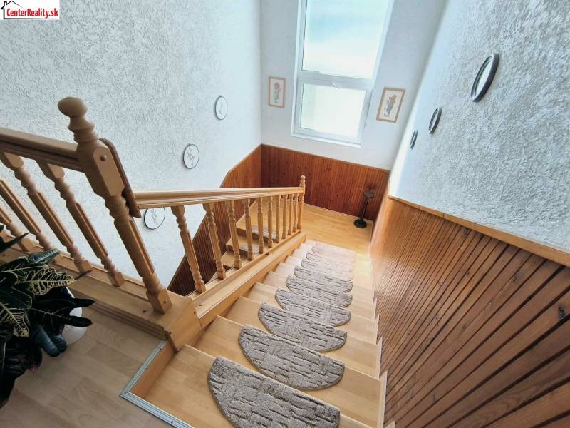 Eine Treppe mit einem Holzgeländer und Dekoration in einem Einfamilienhaus, Boden mit Holzdekor.