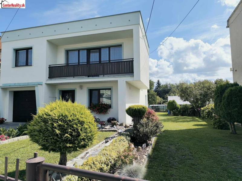 Ein Einfamilienhaus in Partizánske, umgeben von einem Garten mit Bäumen und grünem Rasen.