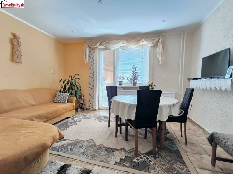 Wohnzimmer eines Einfamilienhauses mit Esstisch, Sofa und Fernseher auf einem Regal.