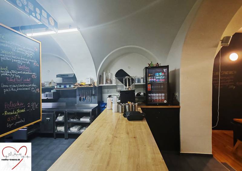 Innenraum eines Gastronomiebereichs mit Holzboden, Arbeitsplatte und Getränkekühlung.