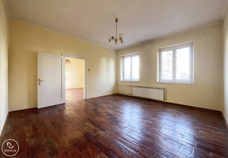 Ein geräumiges Zimmer mit einem Holzboden und zwei großen Fenstern.