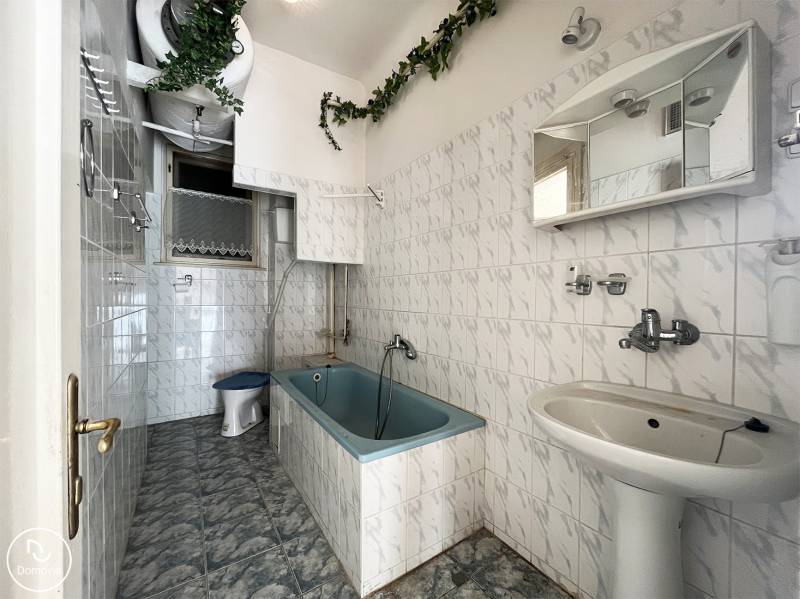 Badezimmer mit Badewanne, weißen Fliesen und grüner Dekoration in einer Wohnung mit 5 oder mehr Zimmern.