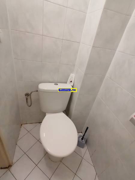 Eine Toilette im Büro mit weißen Fliesen und Boden.
