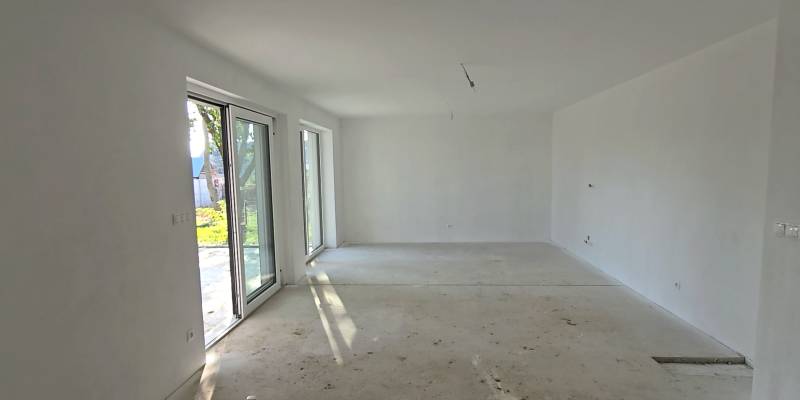 Priestranná miestnosť v rodinnom dome s veľkými oknami a betónovou podlahou.

Großzügiger Raum in einem Einfamilienhaus mit großen Fenstern und Betonboden.