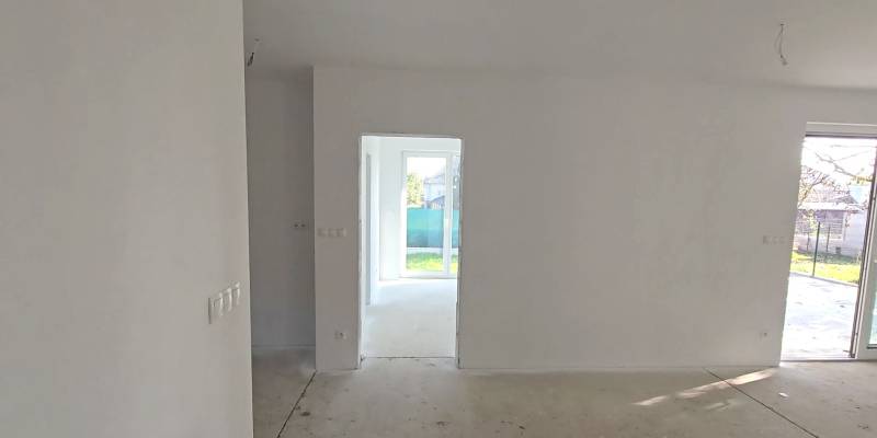 Ein Einfamilienhaus mit einem hellen Raum, weißen Wänden und großen Fenstern zum Garten.