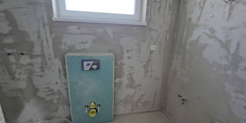 Badezimmerbaustelle in einem Einfamilienhaus mit modernem Installationsrahmen für die Toilette.