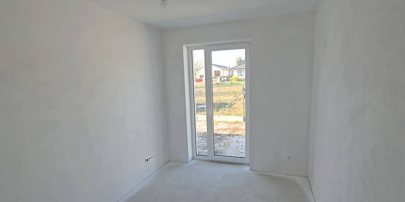 Ein weißer Raum in einem Einfamilienhaus mit einem großen Fenster und Blick auf den Garten.