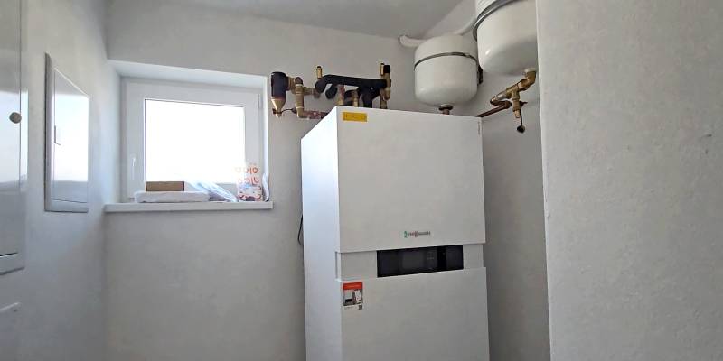 Brennwertkessel in einem hellen Technikraum eines Einfamilienhauses mit Fenster.